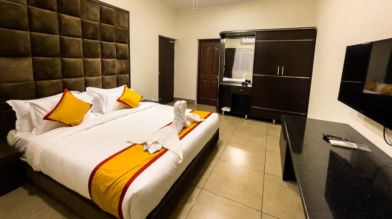 Warm, timber-lined resort suite with a king bed and a balcony overlooking palms